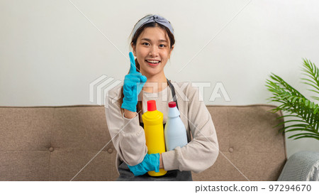 Housekeeper is wearing protective gloves to holding cleanser bottle and smiling to showing happy thumbs up Housekeeper is wearing protective gloves to holding cleanser bottle and smiling to showing happy thumbs up 97294670