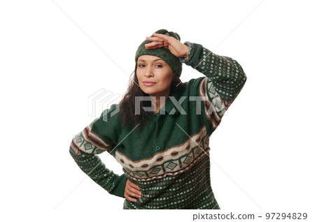 Isolated portrait on white background of charming multi-ethnic curious woman in warm Xmas patterned sweater, holding her hand on forehead and looking into the distance. Copy space for your advertising 97294829