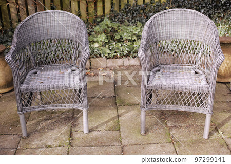 Two relaxing garden chairs and seating in a private and secluded courtyard at home to enjoy mother nature and fresh air. Serene, tranquil and peaceful backyard area with comfortable wicker furniture 97299141