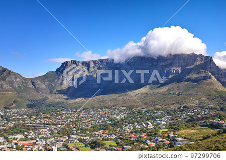 Cumulus clouds forming over Lions Head mountain against a blue sky with copyspace. Panoramic landscape of green mountains with vegetation surrounding an urban city in Cape Town, South Africa 97299706