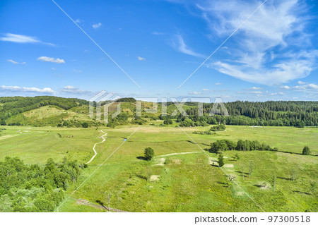 Landscape of a countryside with a cloudy blue sky and copyspace. Wide drone view of green forestry and cultivated grassland. Beautiful landscape of flat land surrounded by forest trees with copyspace 97300518