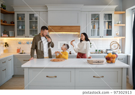 Parents and child eating pizza in living-room at home Parents and child eating pizza in living-room at home 97302913
