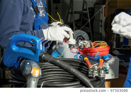 Electricians install cables in plug for charging electric car 97303086