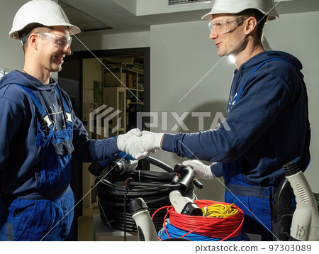 Technicians shake hands and enjoy results of charging plug 97303089