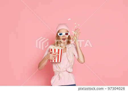 terrified girl watching horror movie , holding bucket of popcorn terrified girl watching horror movie , holding bucket of popcorn 97304026