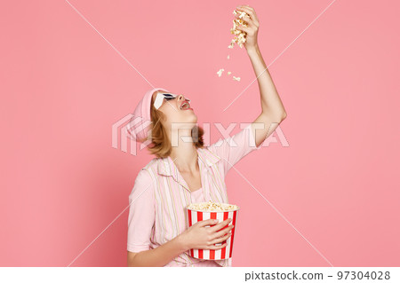 pleased blonde woman in t-shirt and hat eating popcorn pleased blonde woman in t-shirt and hat eating popcorn 97304028