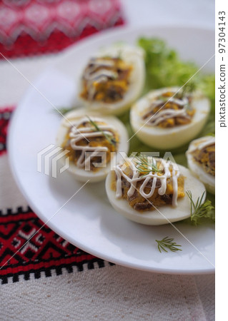 Deviled eggs aka stuffed eggs. Traditional Ukrainian food on the table with embroidered tablecloth. Deviled eggs aka stuffed eggs. Traditional Ukrainian food on the table with embroidered tablecloth. 97304143