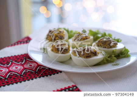 Deviled eggs aka stuffed eggs. Traditional Ukrainian food on the table with embroidered tablecloth. Deviled eggs aka stuffed eggs. Traditional Ukrainian food on the table with embroidered tablecloth. 97304149