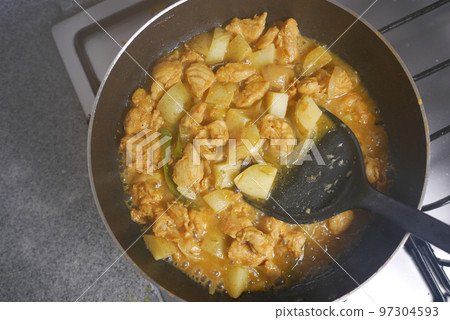 cooking chicken curry in a cooking pan  97304593