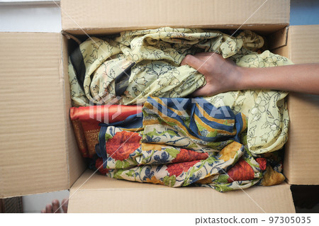 Donation box with donation clothes on a wooden table . Donation box with donation clothes on a wooden table . 97305035