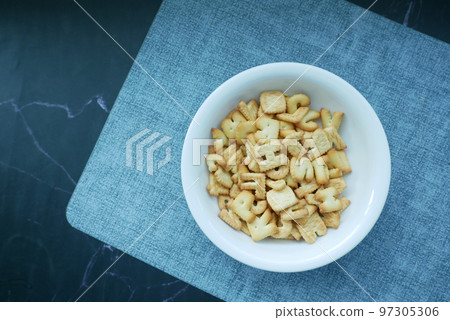 letter shape sweet cookies in a white bowl on black  97305306