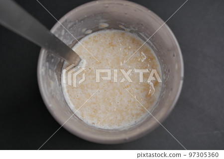 oats, banana and milk in a bowl on black background  97305360