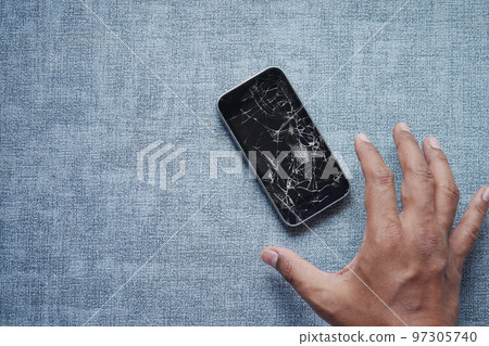 hand reaching from a broken smart phone on table hand reaching from a broken smart phone on table 97305740