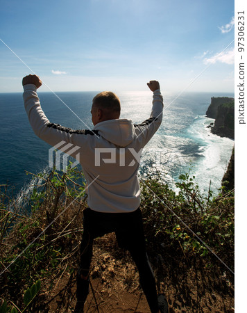 a man stands on a cliff a man stands on a cliff 97306231