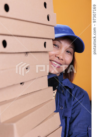 Smiling asian senior delivery employee holding pizza boxes, delivering to client during lunch time. Pizzeria worker hidden behind a large stack of takeout food order. Take out food concept Smiling asian senior delivery employee holding pizza boxes, delivering to client during lunch time. Pizzeria worker hidden behind a large stack of takeout food order. Take out food concept 97307169
