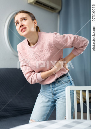 Woman suffering from back pain at home 97310036