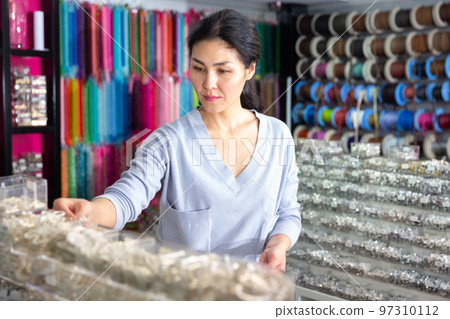 Young adult woman choosing jewelry in store 97310112