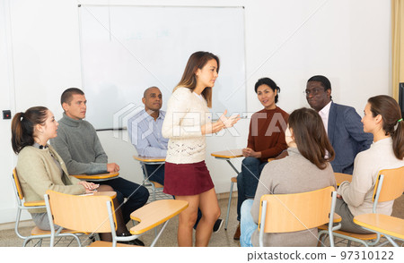 Group of students attentively listening to lecture of female teacher Group of students attentively listening to lecture of female teacher 97310122