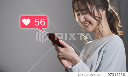 Young woman operating a smartphone at night 97312238