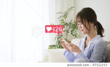 穿著睡衣的年輕女子操作智能手機 97312253