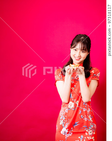 happy asian young asian wearing traditional cheongsam showing gold ingots for celebrating chinese new year on red background happy asian young asian wearing traditional cheongsam showing gold ingots for celebrating chinese new year on red background 97318117