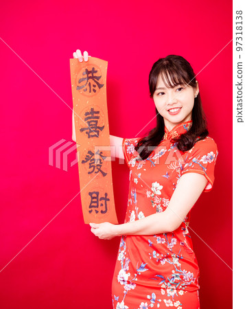 Asian young woman wearing traditional cheongsam to celebrate new year with words meaning new year on red background, china 97318138