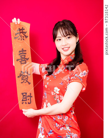 Asian young woman wearing traditional cheongsam to celebrate new year with words meaning new year on red background, china Asian young woman wearing traditional cheongsam to celebrate new year with words meaning new year on red background, china 97318142