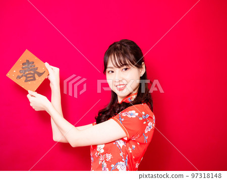 Asian young woman wearing traditional cheongsam to celebrate new year with words meaning new year on red background, china Asian young woman wearing traditional cheongsam to celebrate new year with words meaning new year on red background, china 97318148