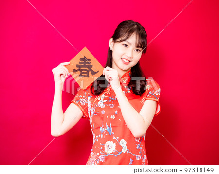 Asian young woman wearing traditional cheongsam to celebrate new year with words meaning new year on red background, china Asian young woman wearing traditional cheongsam to celebrate new year with words meaning new year on red background, china 97318149