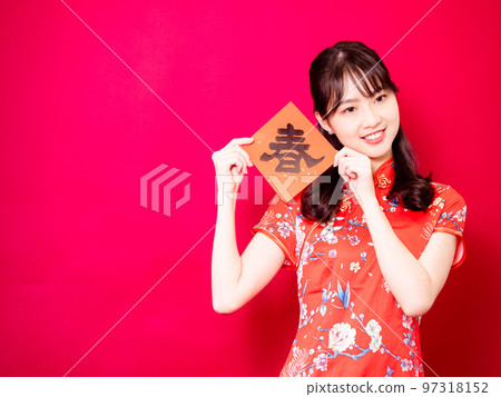 Asian young woman wearing traditional cheongsam to celebrate new year with words meaning new year on red background, china 97318152