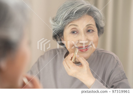 頭髮灰白的老年婦女在照鏡子時塗口紅 97319961