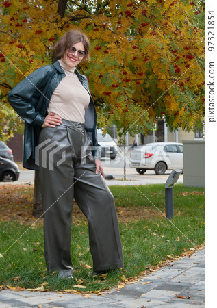 A woman in leather clothes stands against the backdrop of an autumn maple square 97321854