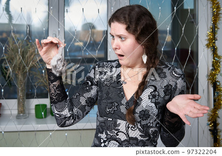 Frightened woman looking at a toy mouse she is holding by the tail 97322204