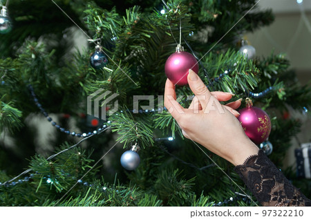 Close-up of female hands decorating a Christmas tree 97322210