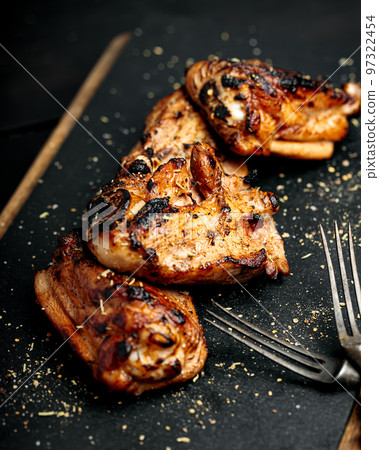 BBQ chicken thighs on a black cutting board. Soft focus. Vertical shot 97322454