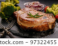 Grilled meat and vegetables. Appetizing pork loin and broccoli on a black stone cutting board. Close-up 97322455