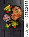 Grilled meat and vegetables. Appetizing pork loin and broccoli on a black stone cutting board. Top view. Vertical shot. Copy space 97322456