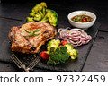 Close-up BBQ pork loin with spicy sauce and vegetables on a black stone board. Selective focus 97322459