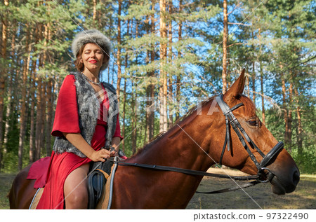 Woman in traditionsl clothes rides a horse in summer forest 97322490