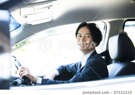 A man driving a car looking at the camera 97332229