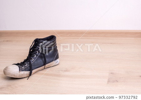 Old torn black shoe on a wooden background Old torn black shoe on a wooden background 97332792