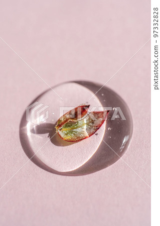 A drop of cosmetic gel with a leaf on a pink background. 97332828