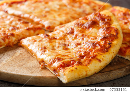 Delicious crispy New York style pizza with melted cheese and base tomato sauce close-up on a wooden board. Horizontal 97333161