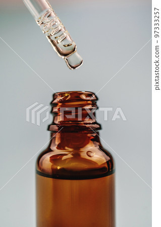 Pipette with cosmetic oil over a brown bottle Pipette with cosmetic oil over a brown bottle 97333257