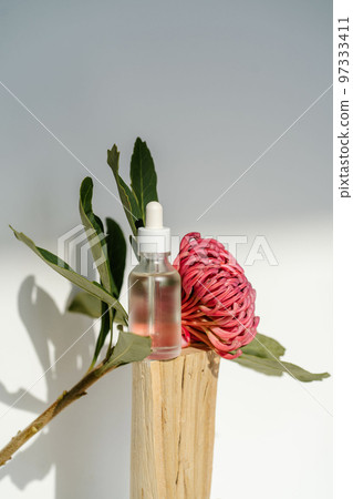 The serum and the flower stand on a piece of wood. 97333411