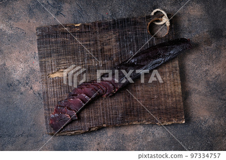 homemade jerky meat on a kitchen cutting board, dark and moody, clouseup 97334757