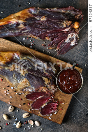 Two smoked lamb leg on a wooden board on dark background 97334857