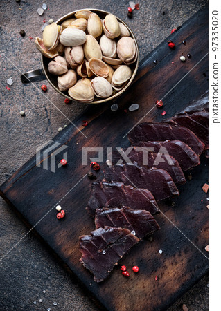 homemade jerky meat on a kitchen cutting board with pistachio homemade jerky meat on a kitchen cutting board with pistachio 97335020