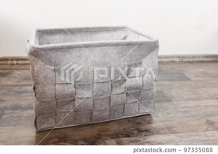 Empty home storage basket made of soft grey felt material. Side view, square pattern, copy space Empty home storage basket made of soft grey felt material. Side view, square pattern, copy space 97335088