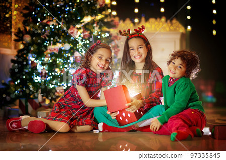 Kids at Christmas tree. Children open presents 97335845